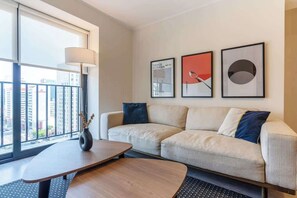 Ein modernes Wohnzimmer mit einer Couch, einem Couchtisch und einer Lampe. Drei gerahmte Kunstwerke hängen an der Wand.