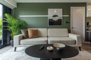 Un salon comprenant un canapé, une table basse, une télécommande et des objets de décoration.