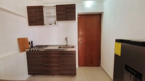 A compact kitchen with a built-in gas stove, a sink, and wooden cabinets. - Tropical Comfort: Your Curaçao Retreat Awaits (Willemstad)