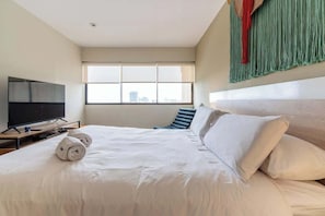 A hotel room with a bed, a TV, and a large window. - Geko | Inviting 2BR in San Isidro w/ Park Views (San Isidro)