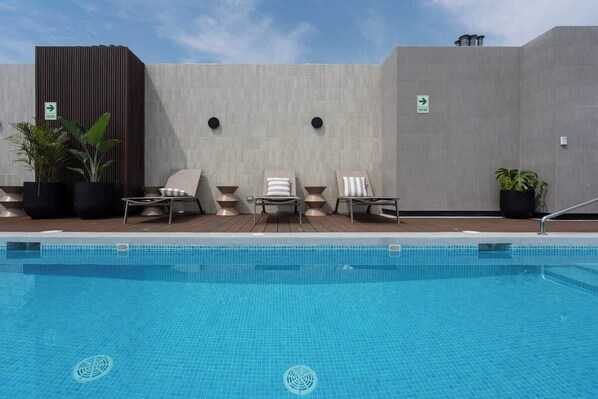 Une piscine avec des chaises longues et des plantes en pot.