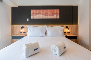 Ein Hotelzimmer mit einem Bett, zwei Nachttischen, einem Wandbild und einer Wandleuchte.