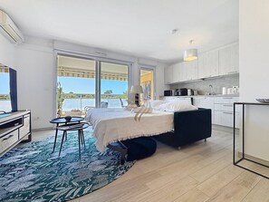A modern bedroom with a bed, a small table, and a view of the sea.