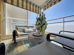 A modern living room with a large window, a sofa, a round coffee table, and a cactus plant. - Serenity Getaway–4 people–WiFi–Terrace–Garage (Saint-Raphaël)