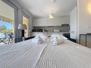 A hotel room with a large bed, a kitchenette, and a view of the outdoors. - Serenity Getaway–4 people–WiFi–Terrace–Garage (Saint-Raphaël)