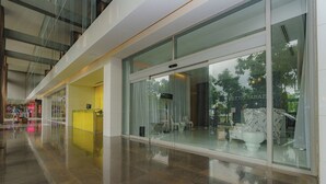 Un moderno vestíbulo de hotel con fachada de vidrio, una recepción y un área de descanso con mobiliario blanco.