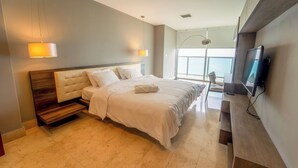 Habitación de hotel moderna con una cama grande, televisión y vista al mar.