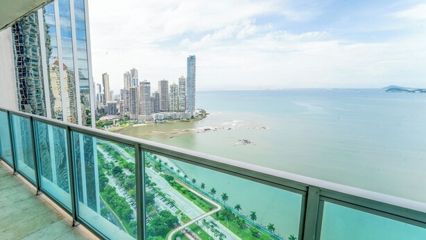 Un edificio alto con vistas a una ciudad costera, incluyendo una playa y un puerto deportivo.
