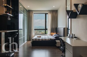 A modern hotel room with a large window, a bed, a desk, and a chair.
