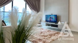 Un salon moderne doté d’une grande fenêtre, d’un téléviseur à écran plat et d’un tapis décoratif.