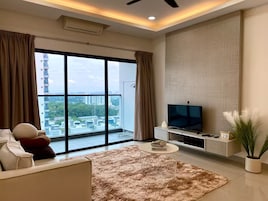 Una sala de estar moderna con un ventanal grande, un televisor de pantalla plana, un sofá y una mesa de centro.