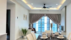 Un espace repas moderne avec une table noire, des chaises blanches et un ventilateur de plafond.
