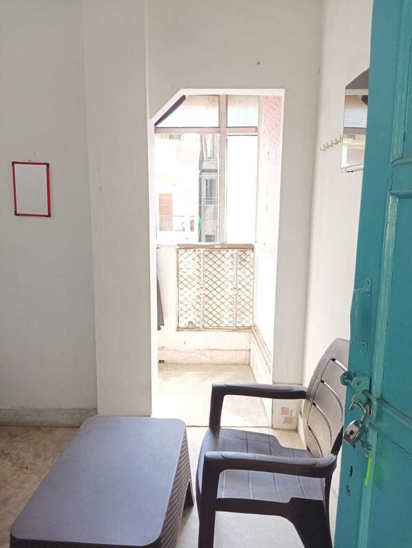 Una habitación con cama, una silla, una mesita, una puerta y vistas al exterior.