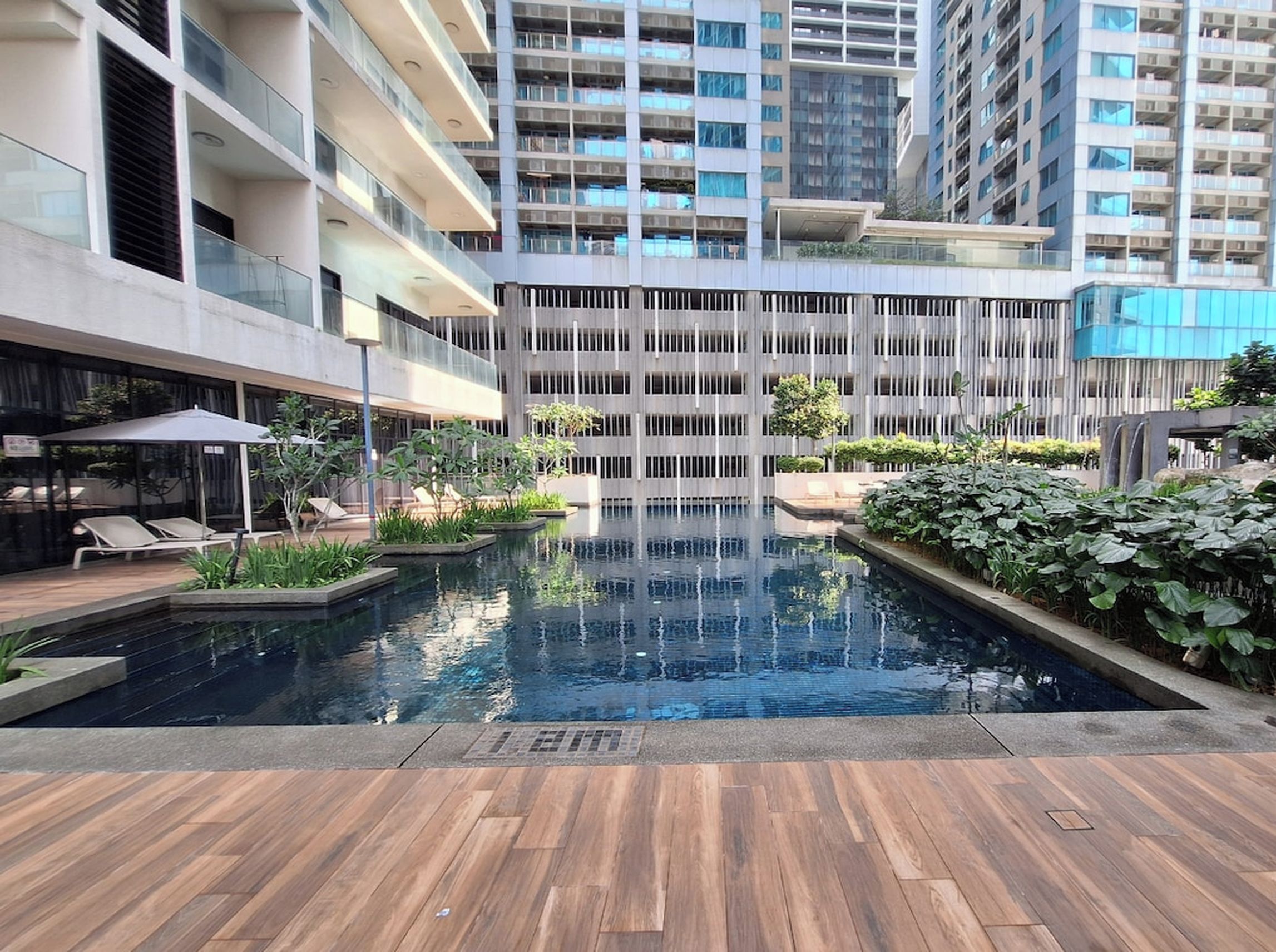 A modern building with a central pool, surrounded by greenery and lounge areas.