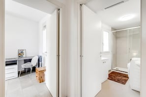 Una habitación moderna y bien iluminada, con escritorio, silla y un taburete de madera.