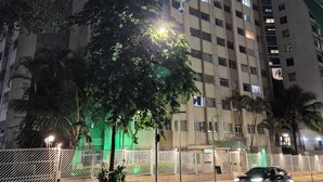 Un immeuble à plusieurs étages, doté d’une façade uniforme, une rue en contrebas où passe une voiture, et un lampadaire éclairant la zone.