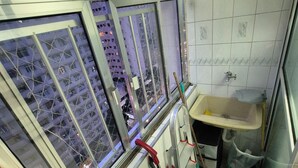 Une petite salle de bain avec une fenêtre, un lavabo et un balai.