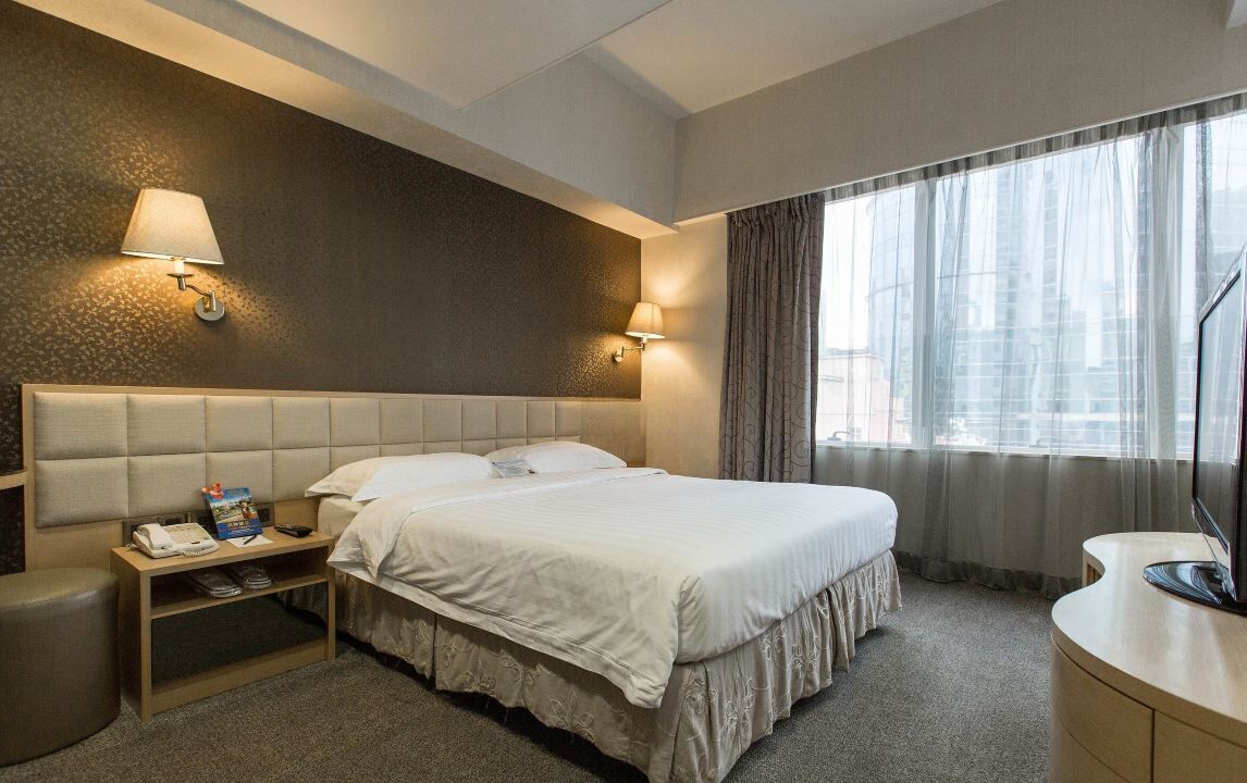 Une chambre d’hôtel avec un grand lit, des lampes de chevet, un bureau avec un téléphone et un téléviseur.