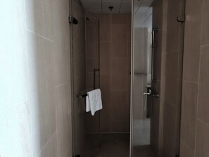 Ein modernes Badezimmer mit Duschkabine aus Glas, einem sichtbaren Handtuchhalter und einer durch die Scheibe erkennbaren Toilette.