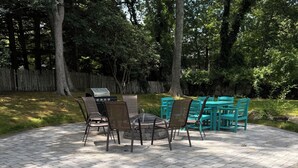 Um pátio externo com lareira de pedra, quatro cadeiras e uma mesa.