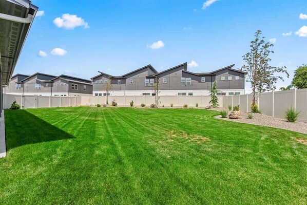 A residential complex with multiple houses, a well-maintained lawn, and a clear sky.