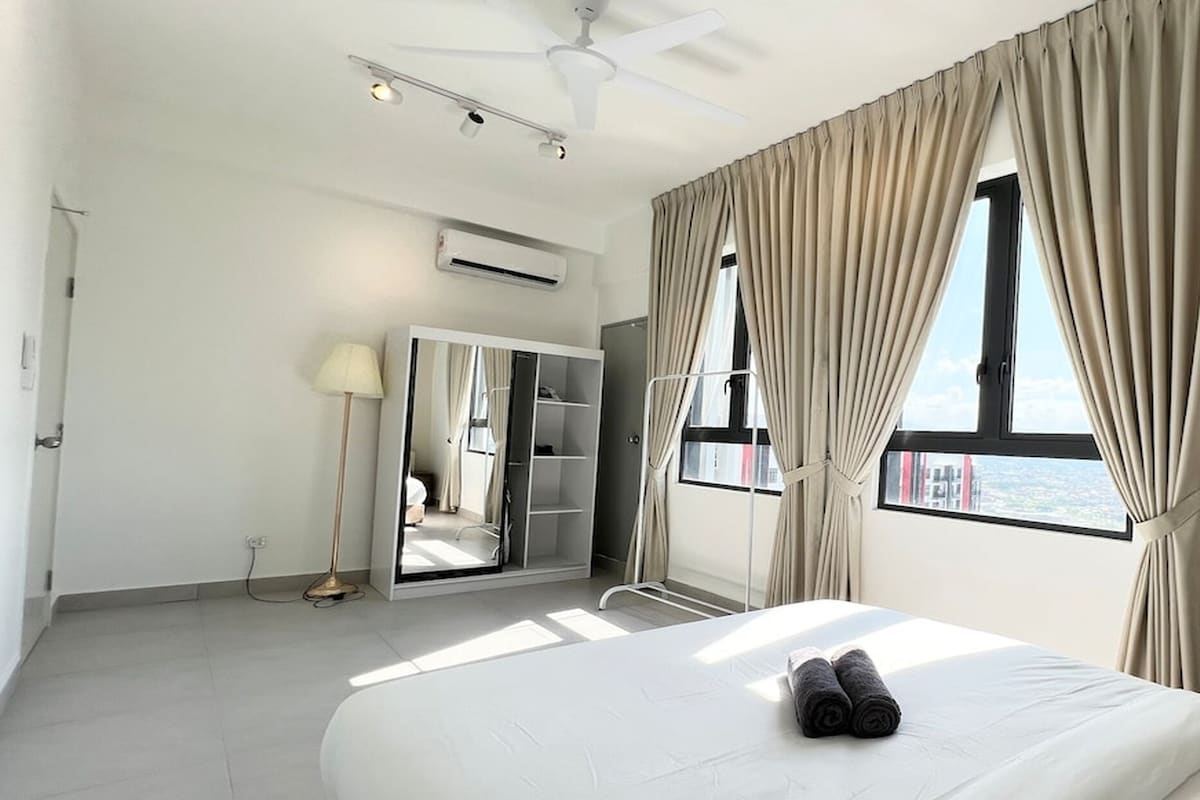 Hotelkamer met een bed, een kledingkast, een plafondventilator, een airconditioner en een raam met gordijnen.