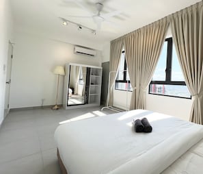 Une chambre d’hôtel comprenant un lit, une armoire, un ventilateur de plafond, un appareil de climatisation et une fenêtre avec des rideaux.