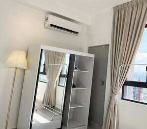 Une chambre moderne équipée d’une armoire, d’un miroir, d’une lampe et d’un appareil de climatisation.