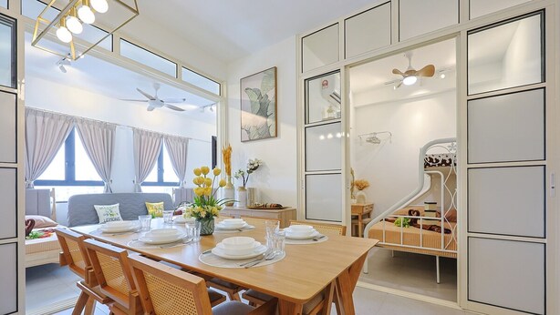 A modern dining area with a wooden table set for four, a sofa in the background, and a child's play area with a slide.