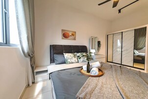 A modern bedroom with a bed, a bedside table, a plant, and a tray with towels.