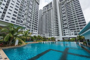 Un moderno edificio residencial de gran altura, con piscina y palmeras.