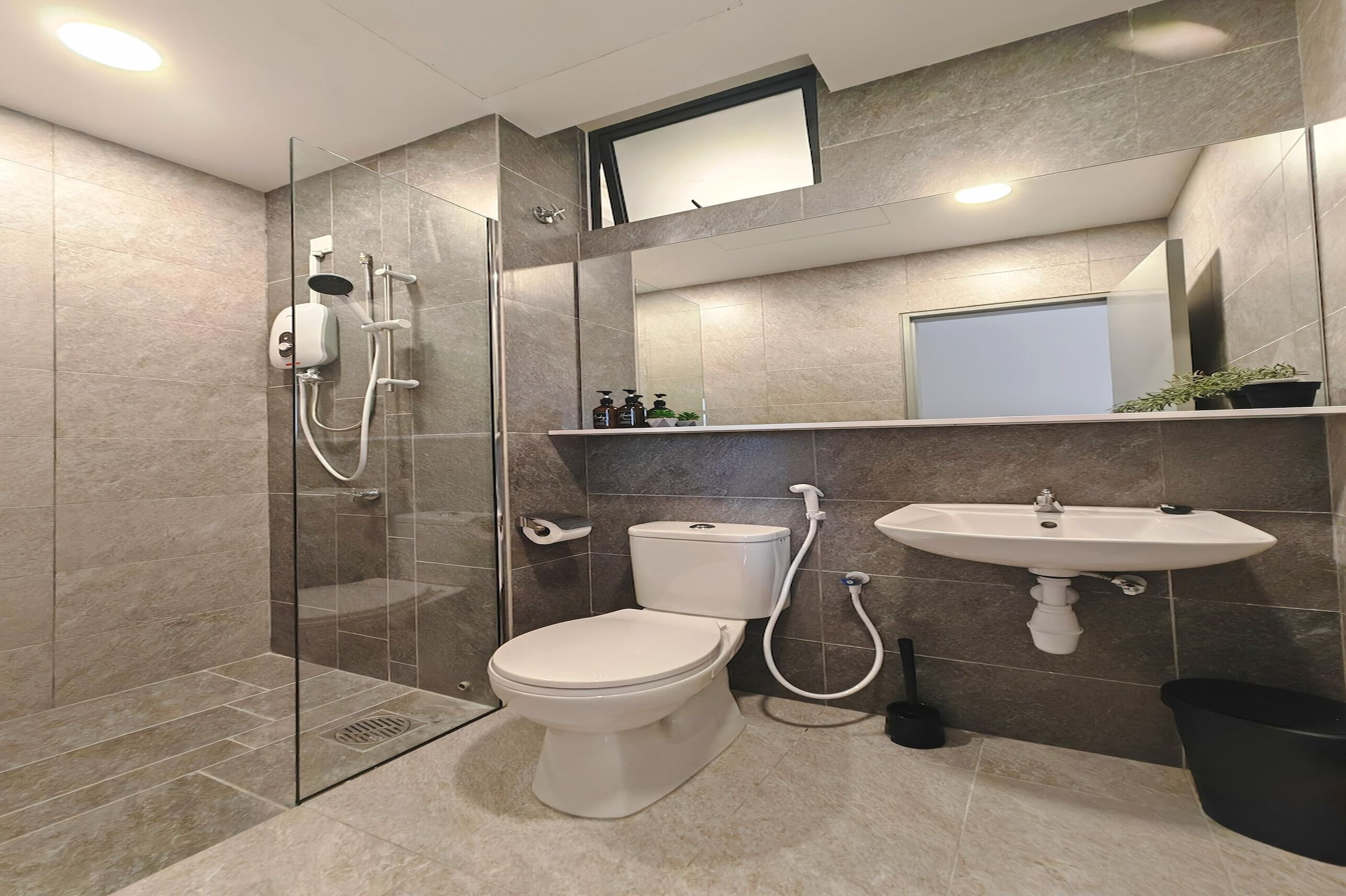 A modern bathroom with a glass-enclosed shower, a toilet, a sink, and a mirror above the sink.