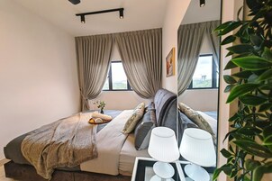 Un dormitorio moderno con cama, mesita de noche, lámpara y cortinas.