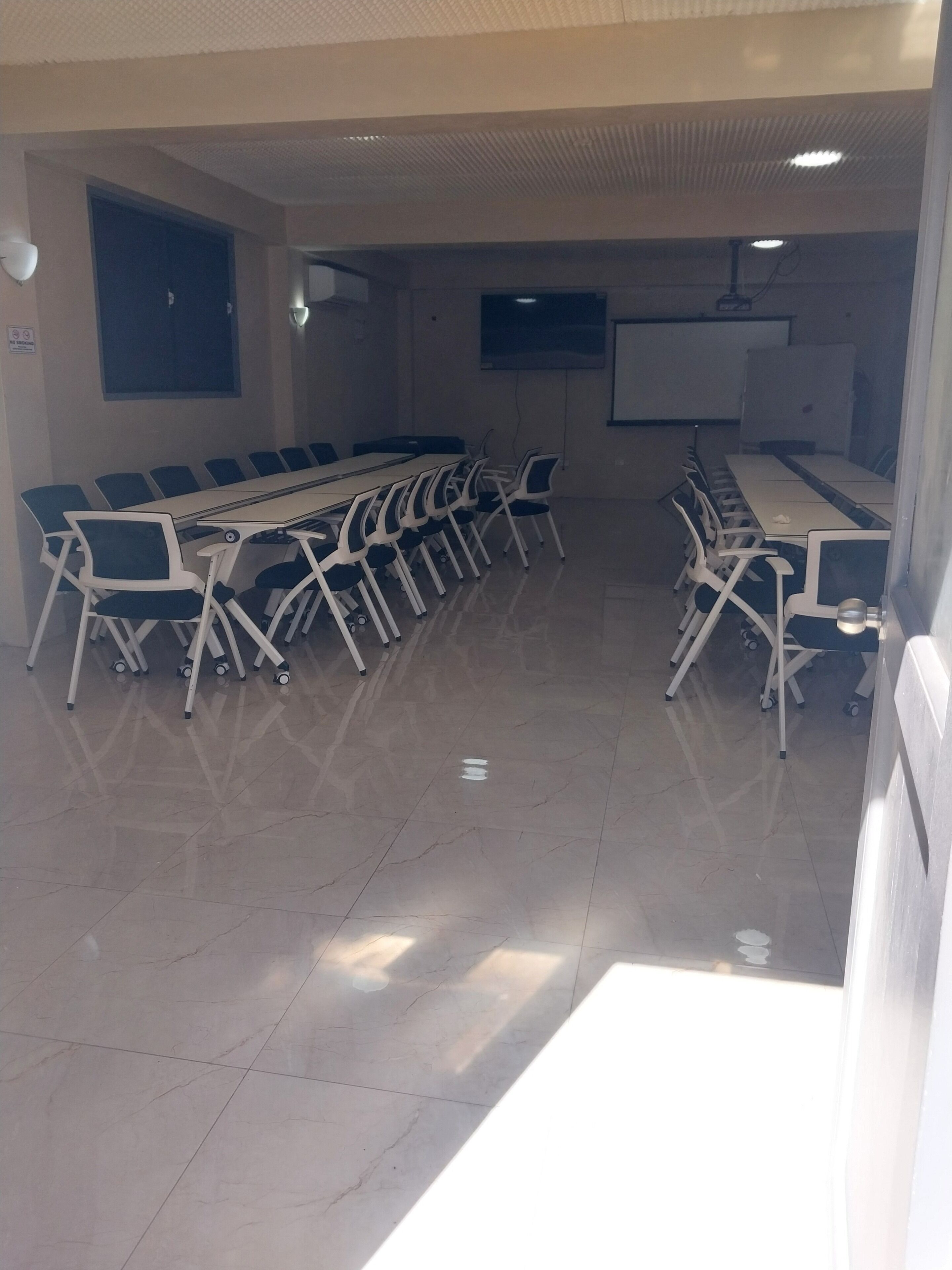 A conference room with a long table and chairs, a projector screen, and a whiteboard.