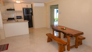 Una cocina moderna con una isla integrada, una mesa de comedor de madera con bancos, y vistas al exterior.