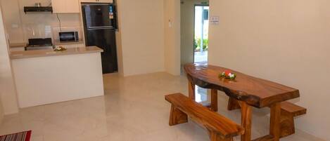 Una cocina moderna con una isla integrada, una mesa de comedor de madera con bancos, y vistas al exterior.