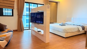 A modern hotel room with a bed, a TV, a wardrobe, and a window with curtains. - Symphony Tower by Emily in Town (Seri Kembangan)