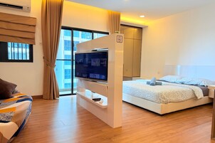 A modern hotel room with a bed, a TV, a wardrobe, and a window with curtains.