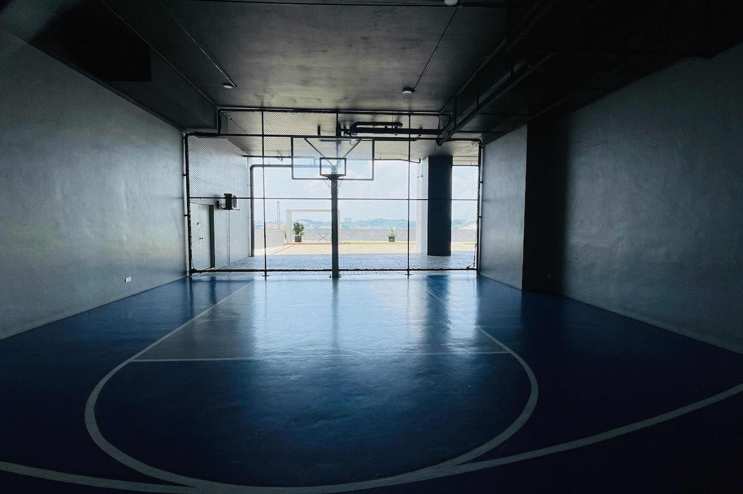 An indoor basketball court with a clear view of the outdoors.