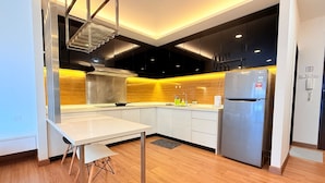 A modern kitchen with white cabinets, a stainless steel refrigerator, and a wooden backsplash. - Symphony Tower by Emily in Town (Seri Kembangan)