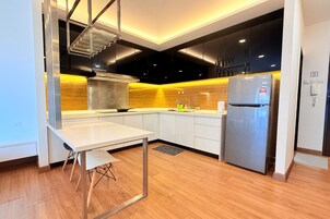 A modern kitchen with white cabinets, a stainless steel refrigerator, and a wooden backsplash.