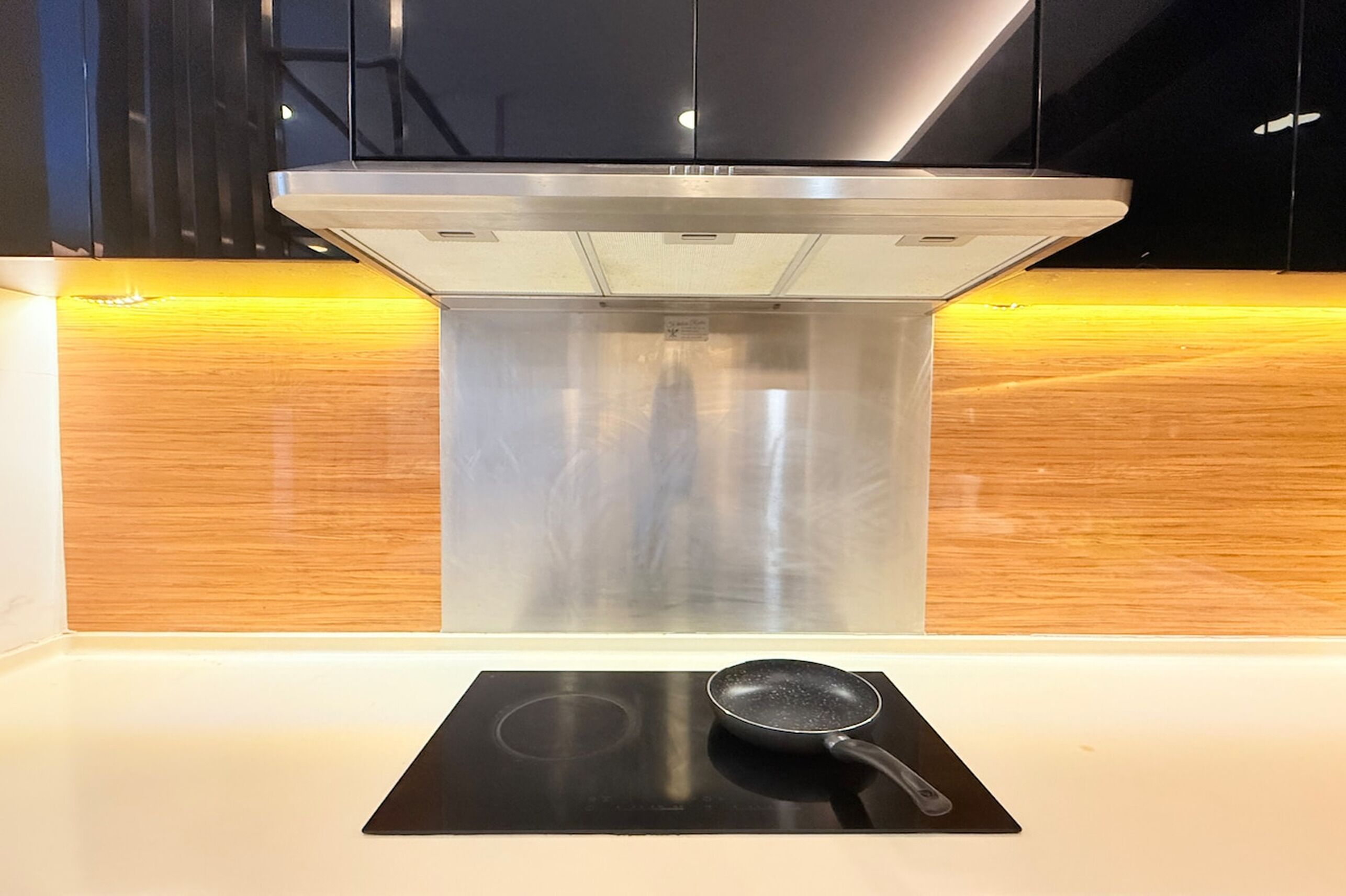 Una cucina moderna con piano cottura a induzione in acciaio inox e una pentola su un tappetino nero per induzione.