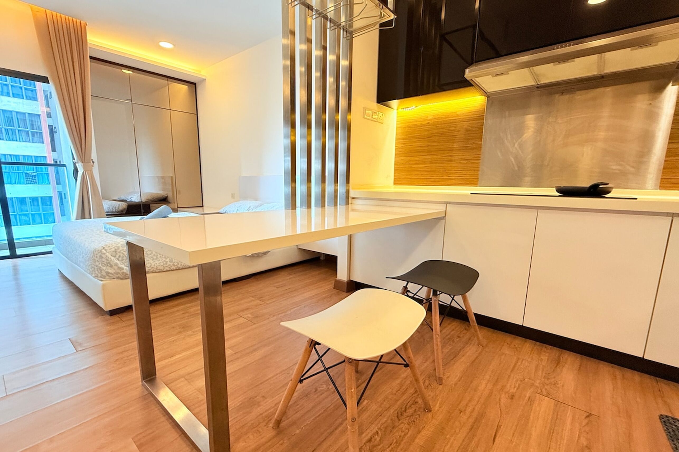 A modern kitchen with a white countertop, two black chairs, and a large window with a view of a building.