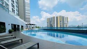 Ein modernes Hotel mit Dachpool, Liegestühlen und Blick auf hohe Gebäude.