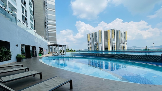 A modern hotel with a rooftop pool, lounge chairs, and a view of high-rise buildings. - Symphony Tower by Emily in Town (Seri Kembangan)