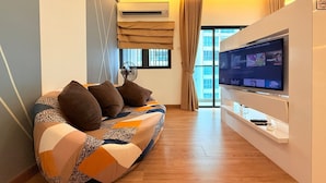 A modern living room with a sofa, a flat-screen TV, and a ceiling fan. - Symphony Tower by Emily in Town (Seri Kembangan)