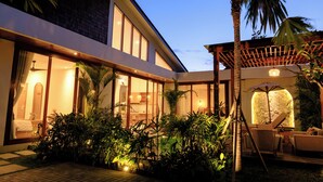 Un edificio moderno con amplios ventanales, un patio cubierto y abundante vegetación.