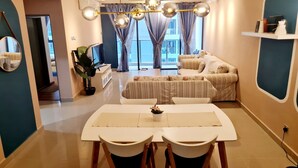 A modern living room with a sofa, dining table, chairs, and a TV. - Amerin Residence Mall Apartments (Seri Kembangan)