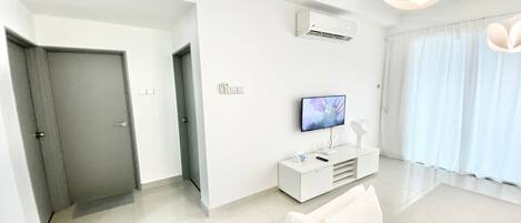 A modern living room with a white sofa, a flat-screen TV, and a minimalist design.