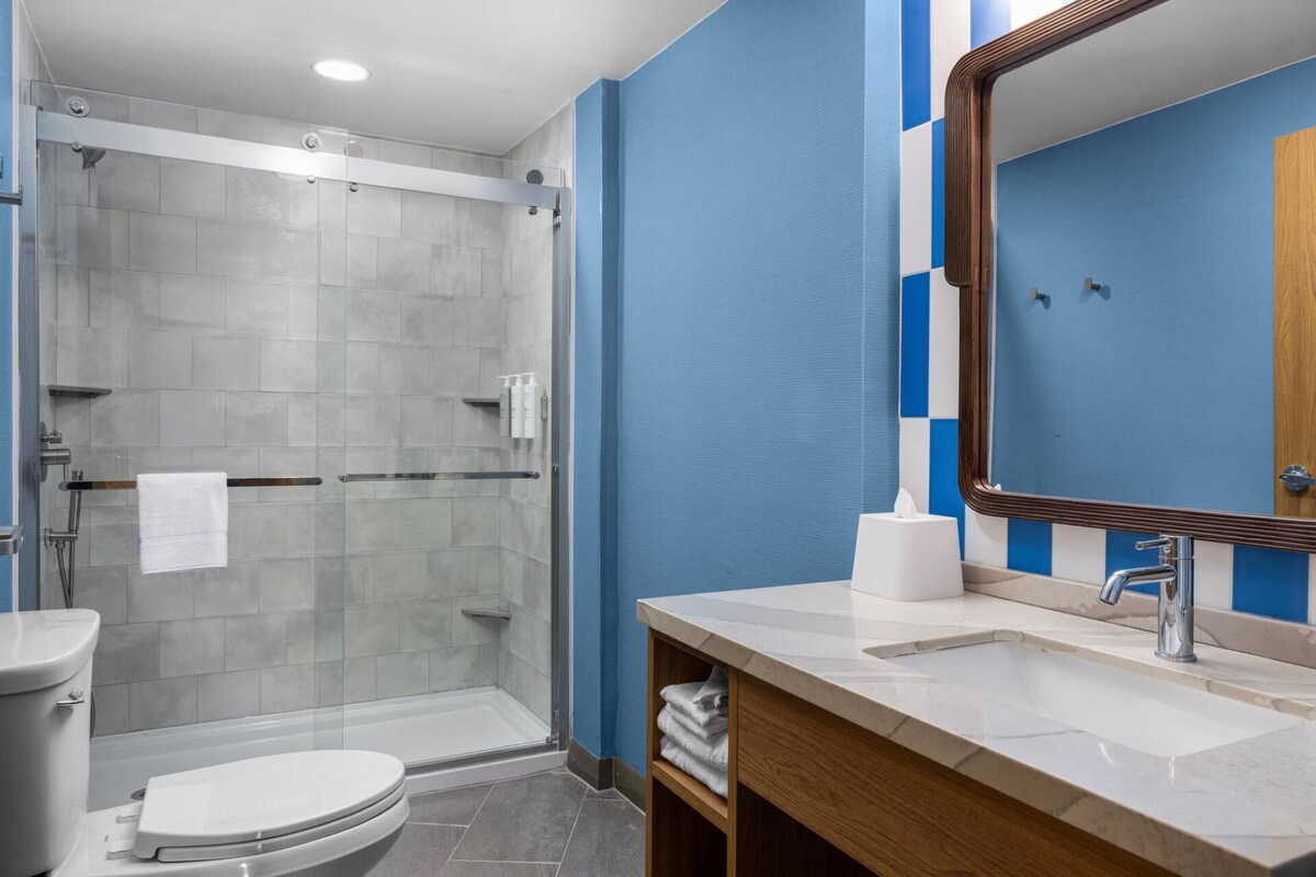 Un bagno con doccia vetrata, un water, un lavandino con specchio e un portascope.